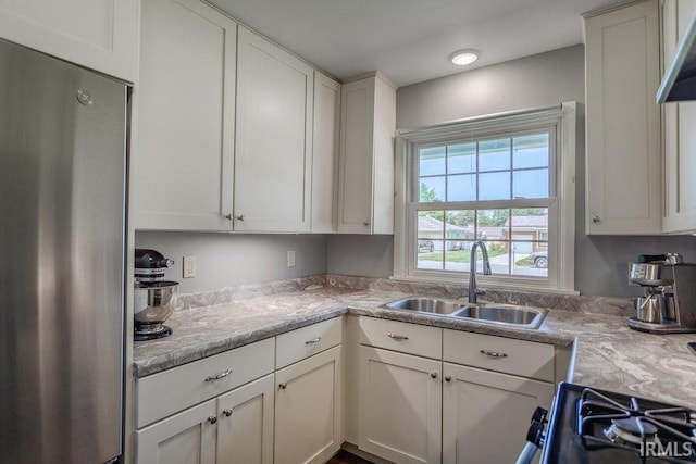 kitchen featuring white cabinets, a sink, and freestanding refrigerator