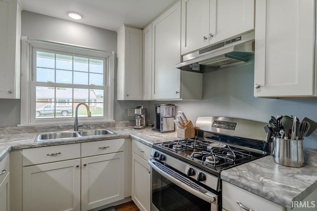 kitchen featuring under cabinet range hood, white cabinets, a sink, and gas range