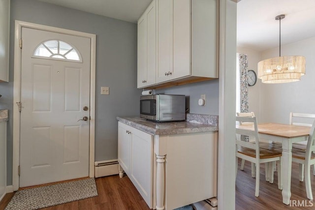 kitchen featuring white cabinets, dark wood finished floors, stainless steel microwave, light countertops, and pendant lighting