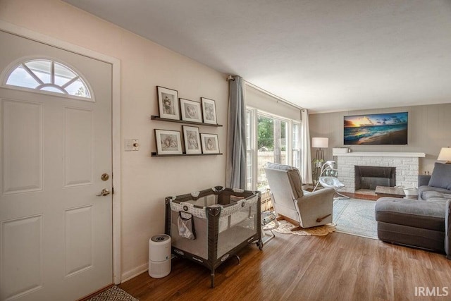 entryway with baseboards, a fireplace with raised hearth, and wood finished floors