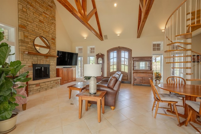 living area with a stone fireplace, beamed ceiling, high vaulted ceiling, and light tile patterned flooring