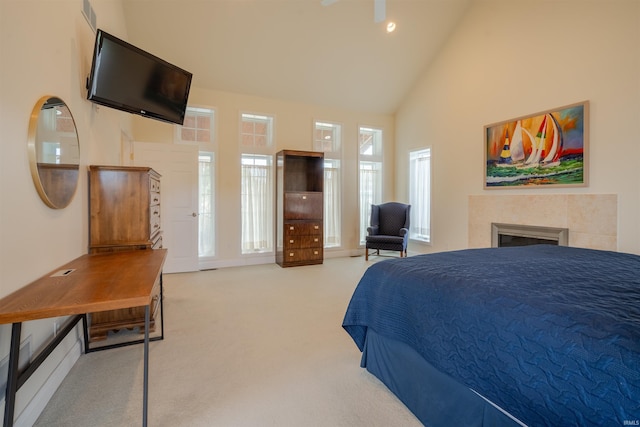 carpeted bedroom featuring a tile fireplace, high vaulted ceiling, and visible vents