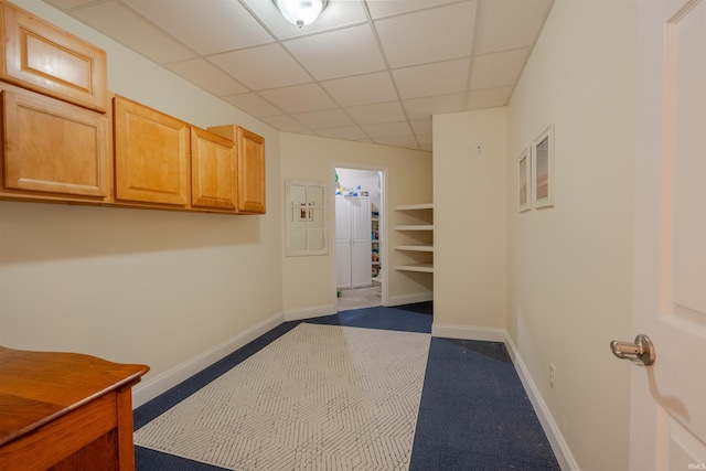 interior space featuring dark carpet, baseboards, and a paneled ceiling