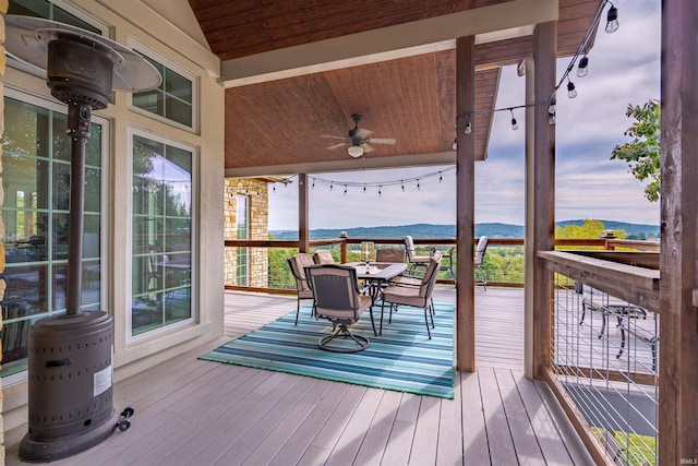 deck with a ceiling fan, a mountain view, and outdoor dining space