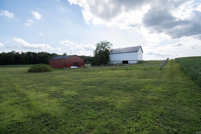 view of yard featuring an outbuilding, a rural view, an outdoor structure, and fence