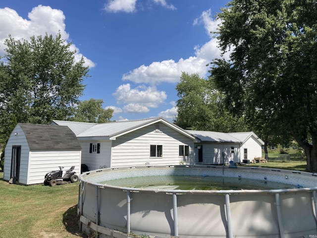 back of house featuring a yard, a storage unit, metal roof, an outdoor pool, and an outdoor structure