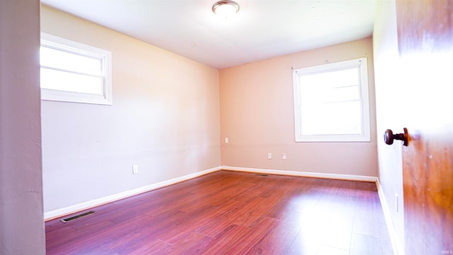 empty room with hardwood / wood-style flooring and a wealth of natural light