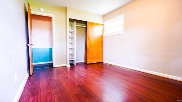 unfurnished bedroom featuring dark wood-type flooring and a closet