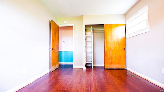 unfurnished bedroom with a closet and dark hardwood / wood-style flooring