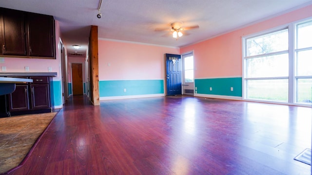 interior space with a textured ceiling, dark hardwood / wood-style flooring, crown molding, rail lighting, and ceiling fan