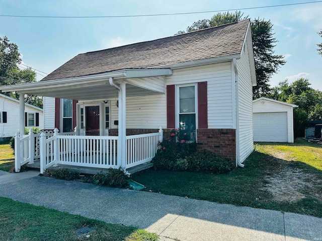 view of front facade with a front lawn, an outdoor structure, covered porch, and a garage