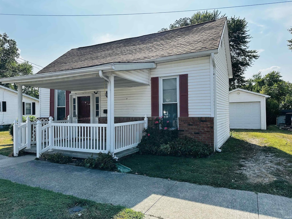 bungalow-style home with an outbuilding, a porch, a shingled roof, a garage, and brick siding