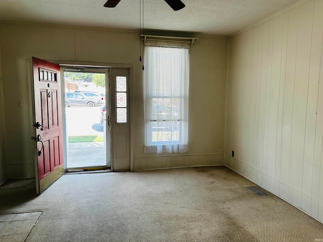 entryway with ceiling fan, plenty of natural light, light carpet, and a textured ceiling