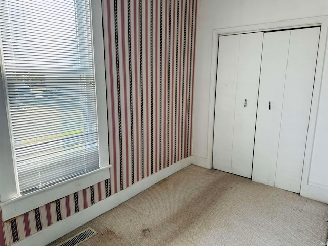 unfurnished bedroom featuring light carpet and a closet