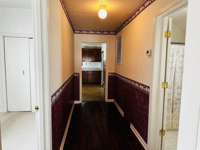 corridor with a textured ceiling and dark carpet