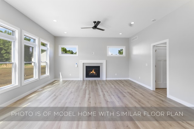 unfurnished living room featuring a warm lit fireplace, recessed lighting, wood finished floors, visible vents, and baseboards