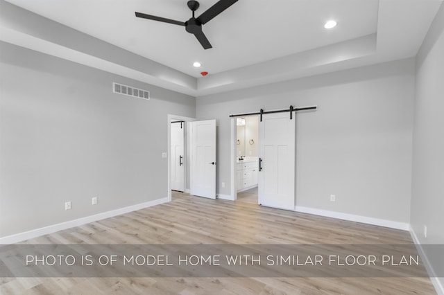 unfurnished bedroom featuring recessed lighting, visible vents, light wood-style flooring, a barn door, and baseboards