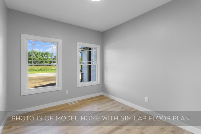 spare room featuring visible vents, baseboards, and wood finished floors