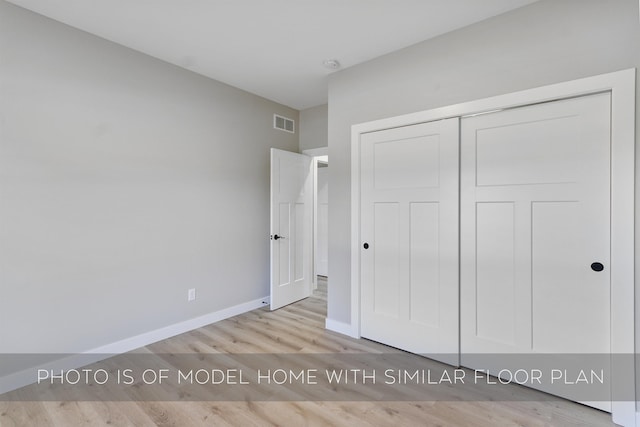 unfurnished bedroom featuring a closet, visible vents, baseboards, and wood finished floors