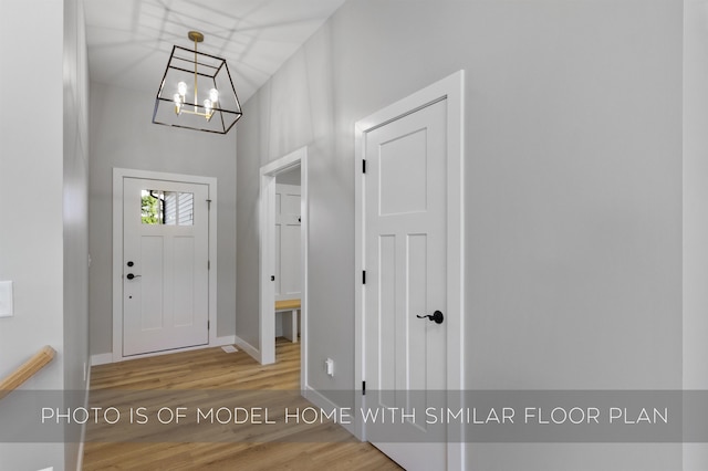 foyer entrance with a notable chandelier, baseboards, and wood finished floors