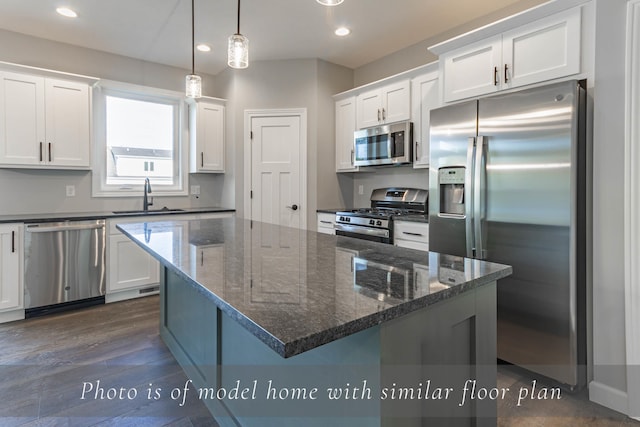 kitchen featuring dark wood finished floors, stainless steel appliances, recessed lighting, white cabinets, and a sink