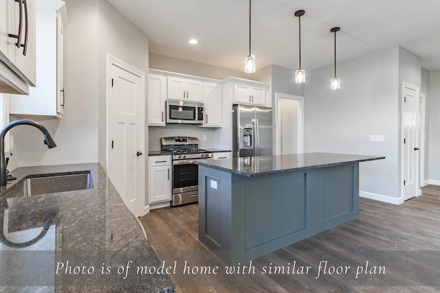 kitchen featuring dark wood-style floors, a center island, appliances with stainless steel finishes, white cabinetry, and a sink