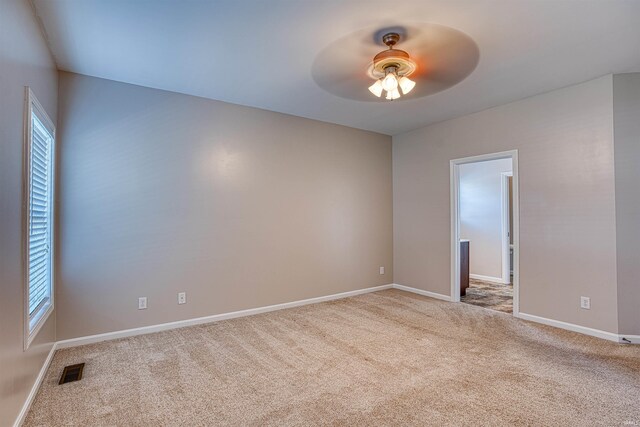 spare room with a wealth of natural light, ceiling fan, and light carpet