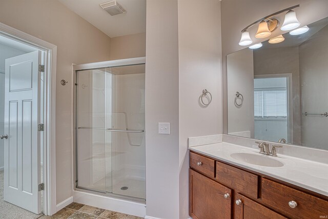 bathroom featuring a shower with shower door and vanity