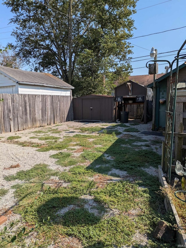 view of yard featuring a storage shed, fence, and an outdoor structure