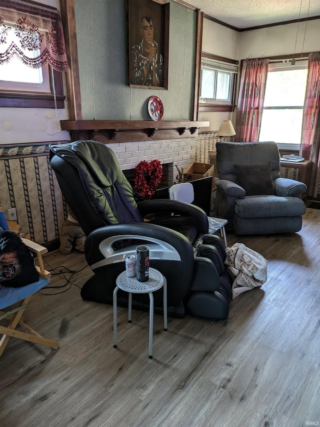 living room featuring a textured ceiling, a brick fireplace, wood finished floors, and crown molding