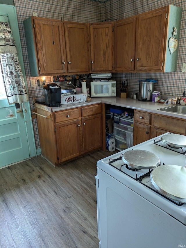 kitchen featuring light countertops, white appliances, light wood-style flooring, and brown cabinets