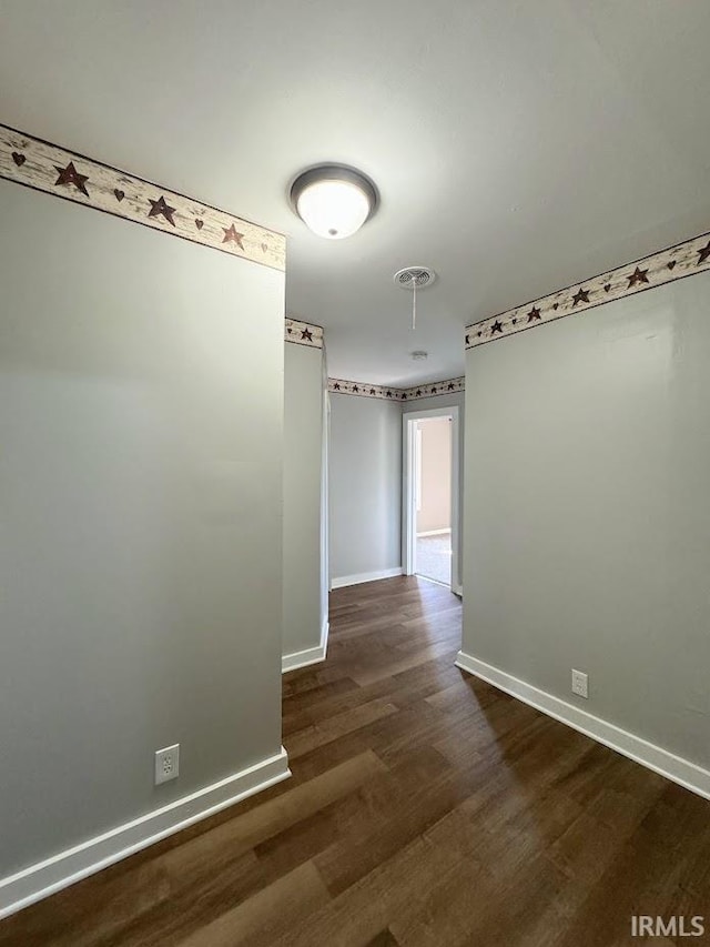 hall featuring visible vents, baseboards, and dark wood finished floors