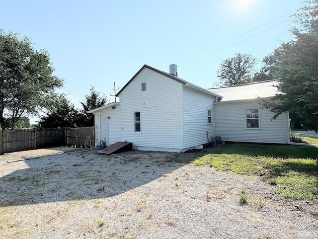 rear view of house featuring fence, metal roof, and cooling unit