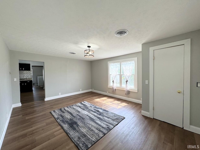 interior space featuring baseboards, a textured ceiling, visible vents, and dark wood-type flooring