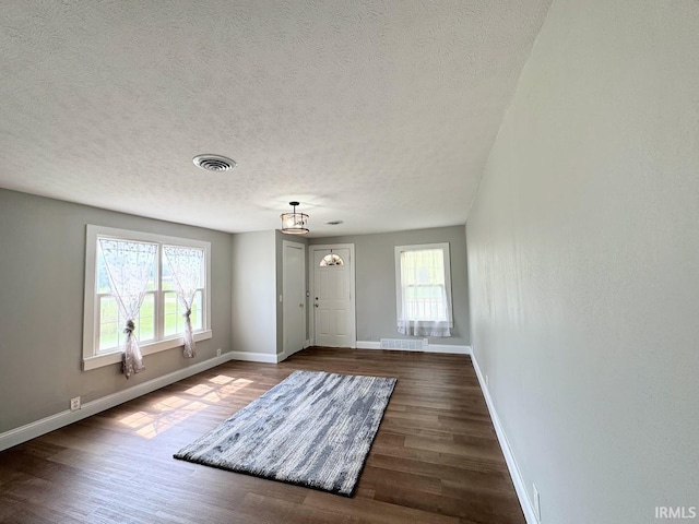 entryway with visible vents, plenty of natural light, baseboards, and wood finished floors