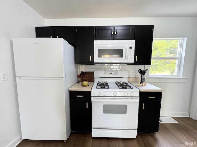 kitchen with white appliances, dark wood-style flooring, backsplash, and dark cabinetry