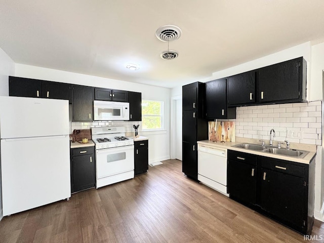 kitchen featuring white appliances, dark cabinetry, a sink, and visible vents