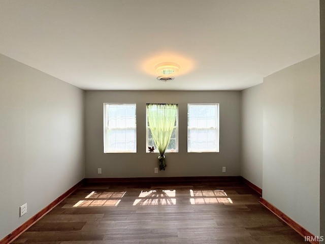 spare room featuring visible vents, baseboards, and wood finished floors