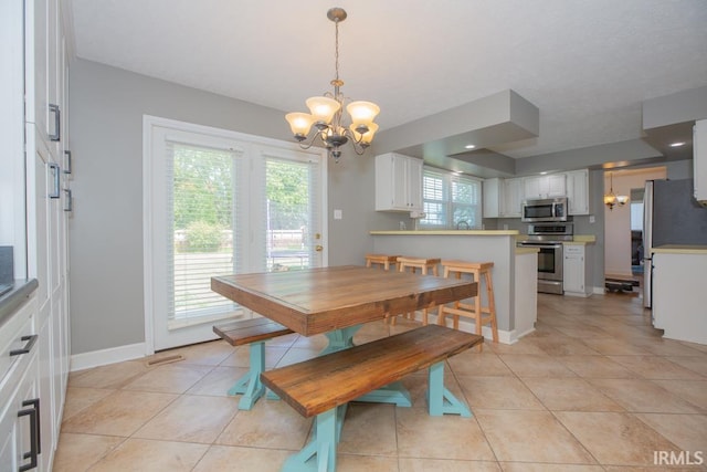 tiled dining area featuring a notable chandelier and a healthy amount of sunlight