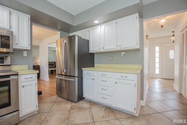 kitchen with light tile patterned floors, white cabinetry, and stainless steel appliances