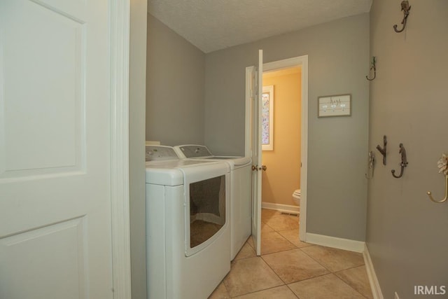 laundry area featuring light tile patterned floors, a textured ceiling, and washer and clothes dryer