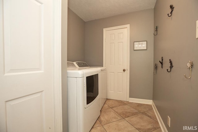 washroom with washing machine and clothes dryer, light tile patterned flooring, and a textured ceiling