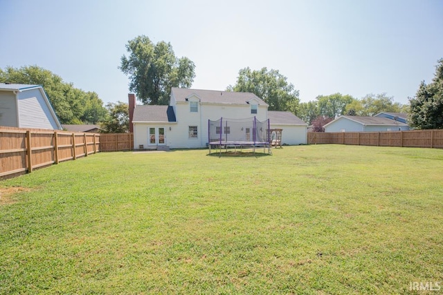 rear view of property featuring a lawn and a trampoline