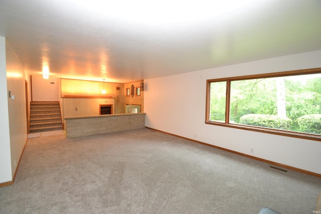 unfurnished living room featuring wooden walls, a fireplace, and carpet floors