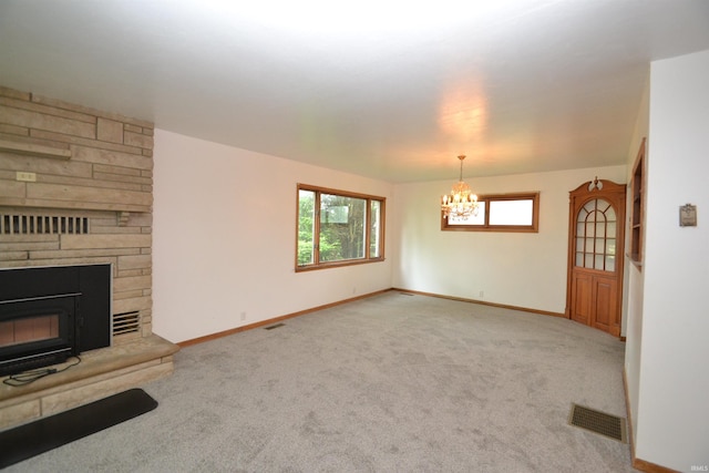 unfurnished living room featuring light colored carpet, a fireplace, and a notable chandelier