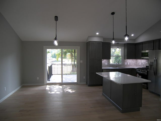 kitchen featuring lofted ceiling, light wood-style flooring, a sink, appliances with stainless steel finishes, and backsplash