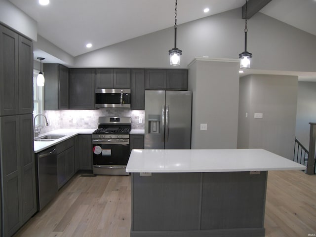 kitchen featuring lofted ceiling with beams, appliances with stainless steel finishes, decorative light fixtures, light wood-style floors, and a sink