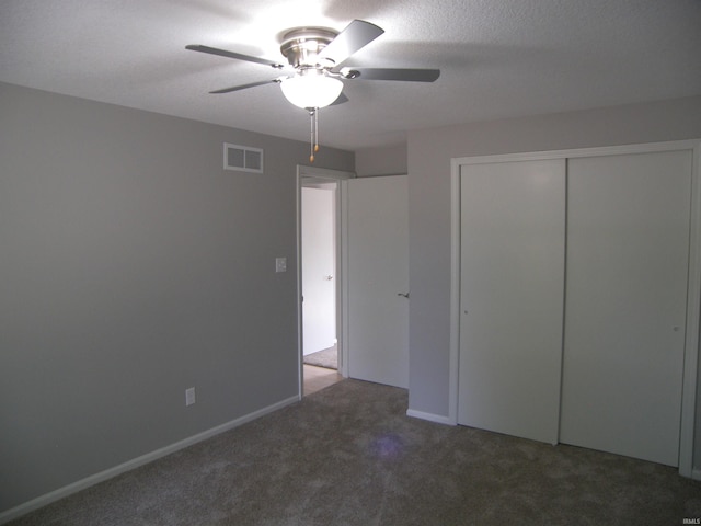 unfurnished bedroom with a textured ceiling, ceiling fan, carpet floors, visible vents, and a closet