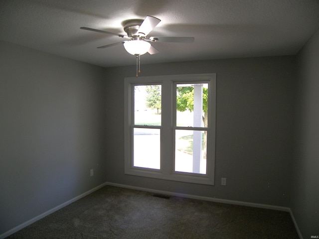 unfurnished room featuring a ceiling fan, dark colored carpet, visible vents, and baseboards