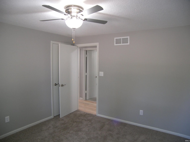 carpeted spare room featuring a ceiling fan, baseboards, visible vents, and a textured ceiling